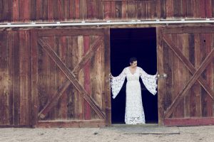 bride-wearing-white-lace-crochet-dress-in-barn