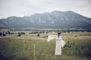 bride-wearing-boho-lace-dress-with-bell-sleeves-with-scenic-background