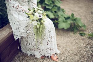 white-bohemian-lace-gown-shown-with-flower-bouquet