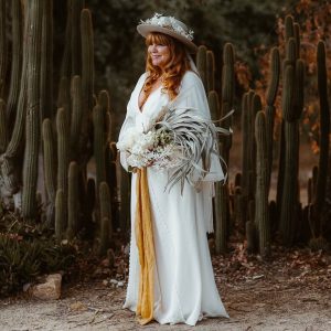 Boho Bride wearing silk bell sleeves gown and hat with dried florals