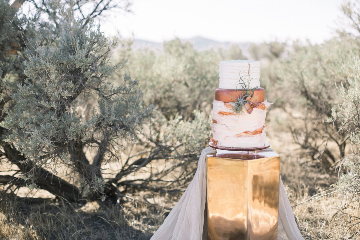 earthy-wedding-cake-inspiration-on-a-copper-stand-with-flax-natural-cotton-cloth-nestled-in-the-mountains