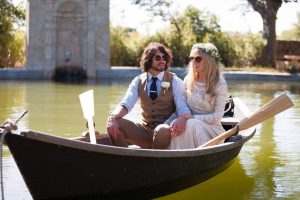 bride-and-groom-in-row-boat-in-the-south-of-France-her-in-a-boho-lace-wedding-dress-wearing-raybans
