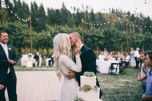 lizzy-and-Dan-sharing-amoment-at-their-outdoor-wedding-venue-filled-with-string-lights-her-in-a-boho-chic-long-sleeve-dress-in-modest-dresses