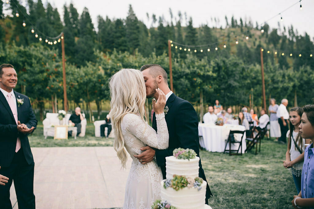 lizzy-and-Dan-sharing-amoment-at-their-outdoor-wedding-venue-filled-with-string-lights-her-in-a-boho-chic-long-sleeve-dress