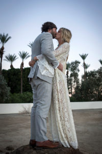bohemain-loving-bride-wearing-a-lace-caftan-finished-with-a-fishtail-raid-and-flowers-in-her-hair-at-her-palm-springs-wedding