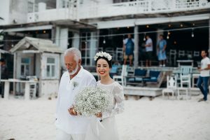 the-smile-on-bride-Carolina's-face-as-she-walks-with-her-dad-carrying-a-baby's breath-bouqet