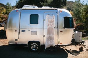 dreamers-and-lovers-lisa-boho-lace-wedding-dress-hanging-in-front-of-an-airstream