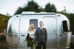 bride-and-groom-standing-in-front-of-a-vintage-airstream