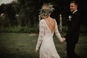 walking-hand-in-hand-her-in-a-romantic-flowy-wedding-dress-with-small-train