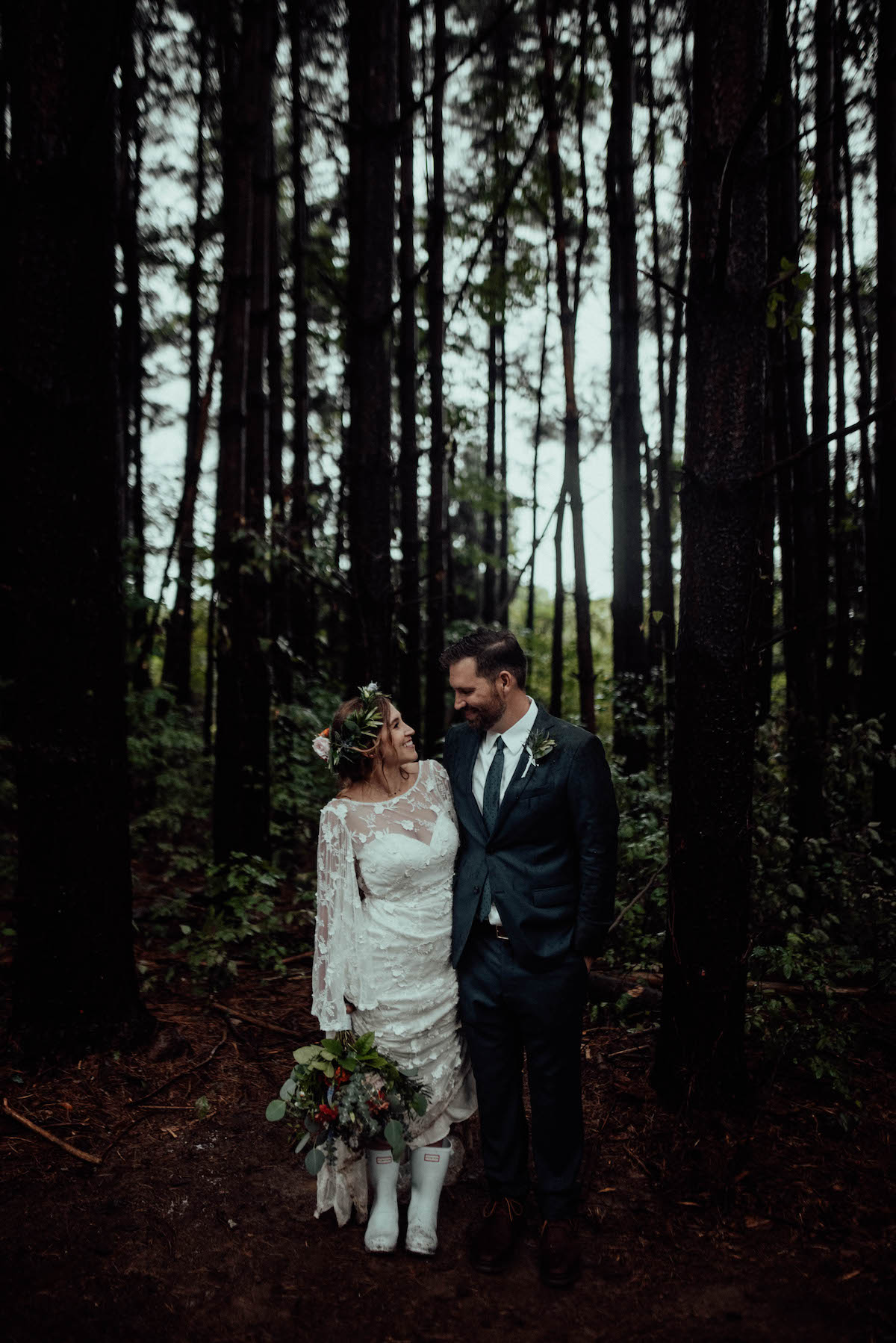 Bride wearing rain boots with her lace wedding dress