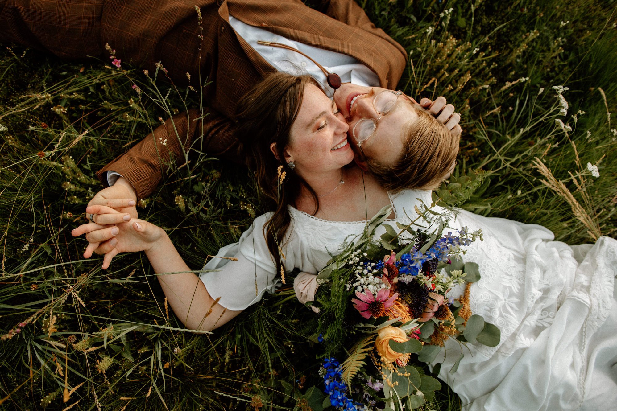 the-happy-bride-and-grrom-laying-in-grass-and-wildflowers-boho-wedding-inspiration