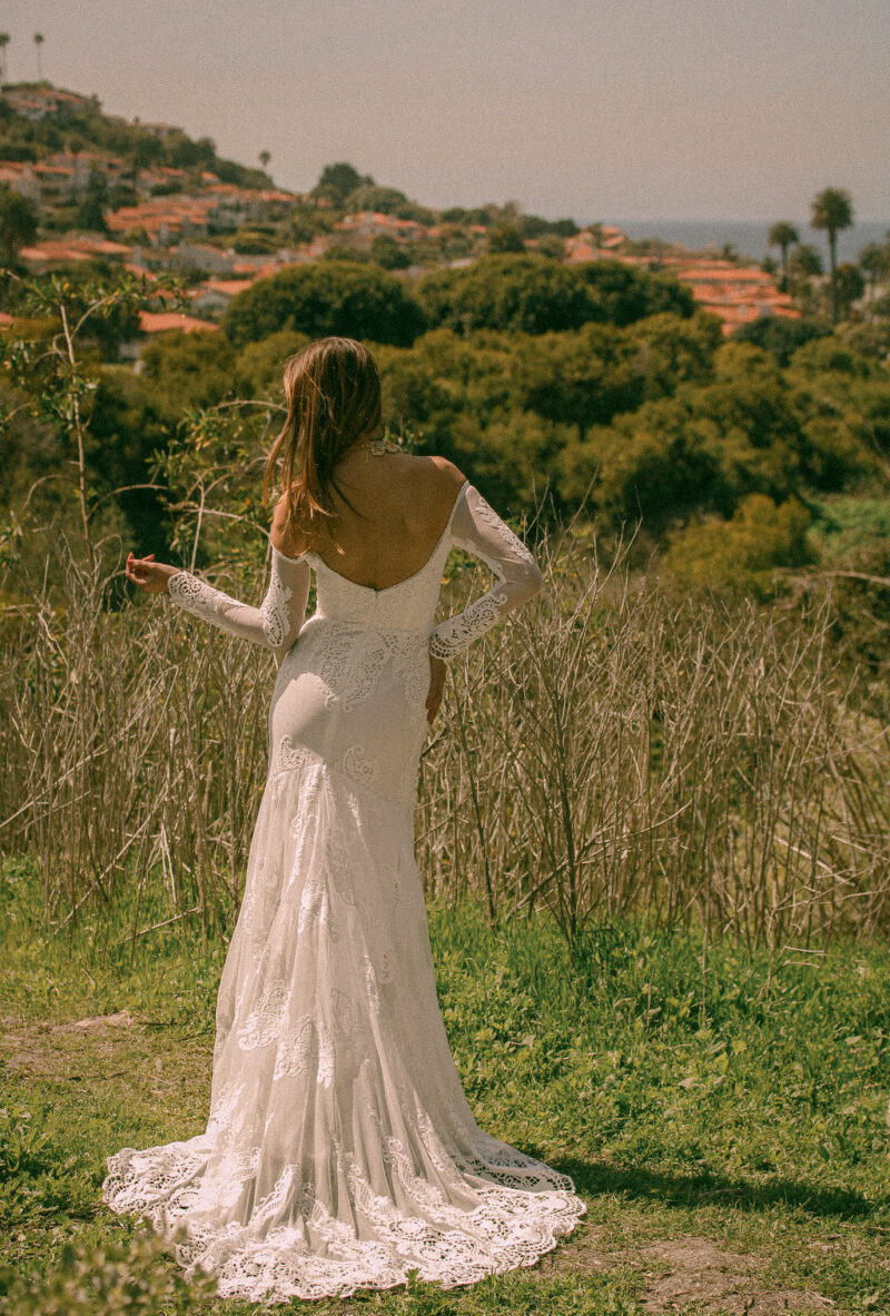 Off the shoulder long sleeve wedding dress back view with hand-cut cotton lace appliqués and dipped back detail - Solstice by Dreamers and Lovers
